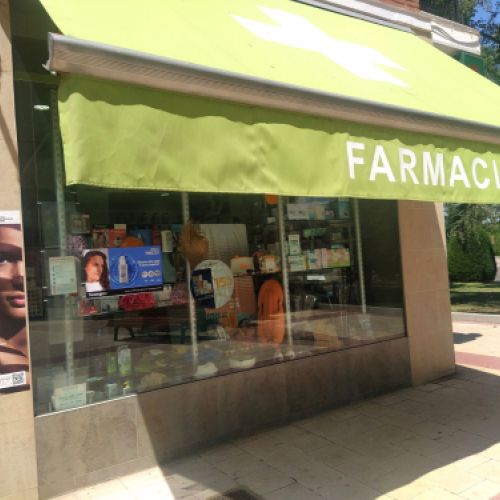Exterior de la farmacia con escaparate y toldo de color verde